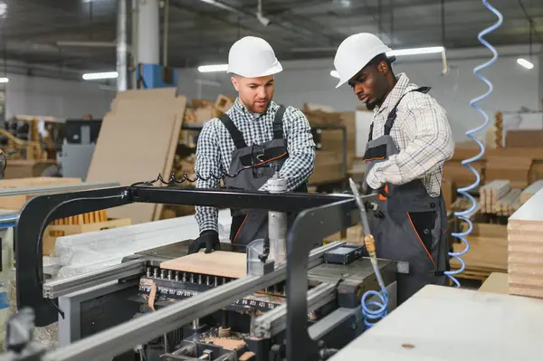 Mobilya üretim tesisinde, mobilya parçaları üreten iki fabrika işçisi