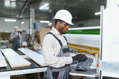 Modern bir üretim tesisinde hassas ahşap kesme ve mobilya üretimi için bilgisayar sayısal kontrol makineleri kullanan yetenekli bir marangoz.