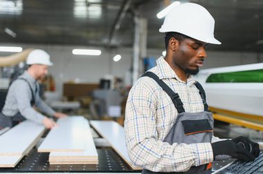 Modern bir ahşap fabrikasında mobilya parçaları üreten iki fabrika işçisi.