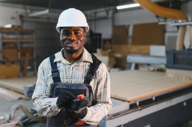 Mobilya fabrikasındaki bir cnc makinesini kontrol eden marangoz modern üretim süreçlerini vurguluyor.