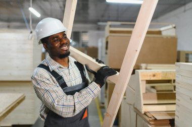 Afrika kökenli Amerikalı işçiler mobilya fabrikasında ahşap kalaslar taşıyorlar, modern makinelerle işçilik ve üretim süreçleri sergiliyorlar.