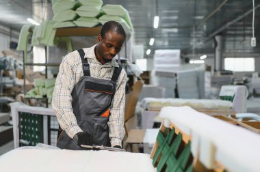 Afrika kökenli Amerikalı işçiler modern bir mobilya fabrikasında bir kanepe yapmaya odaklanırlar, hassas ahşap işçiliği için bir cnc makinesi kullanırlar.