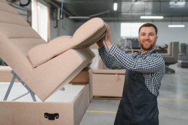 Bir mobilya fabrikasında kanepe monte eden bir zanaatkar, marifetli işçilik ve üretim sürecinde kaliteye olan bağlılığını sergiliyor.