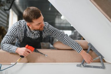 Marangoz, bir mobilya fabrikasında havalı bir tornavidayla şık bir kanepeyi monte ediyor. Yetenekli işçilik ve hassasiyet sergiliyor.