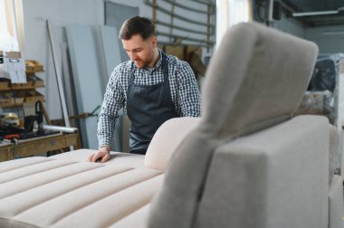 Marangoz, işlek bir mobilya fabrikasında el yapımı bir kanepenin kalitesini inceliyor. Üretim sürecinde hassasiyet ve mükemmellik sağlıyor.