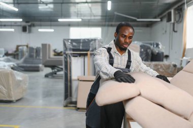 Mobilya fabrikasında bir koltukta çalışan yetenekli bir zanaatkar, kalite kontrolü ve zanaatkarlığı gösteriyor.