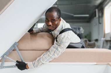 Marangoz hünerli bir şekilde mobilya fabrikasında kanepe montajı, el işi ve imalat sürecinde kendini adamışlık sergiliyor.