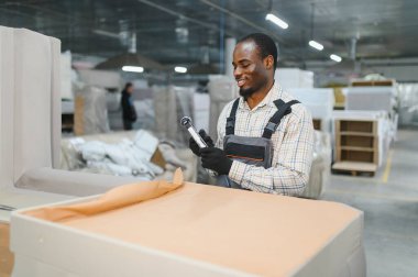 Mobilyacı, yoğun bir mobilya fabrikasında kalite kontrolü sağlayan barkod tarayıcısı ile kanepe bölümünü tarıyor.