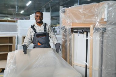 Bir mobilya fabrikasında kanepe üretimiyle ilgilenen Afrikalı Amerikalı işçiler, ahşap ve montajda hassasiyet için bir cnc makinesi kullanıyorlar.