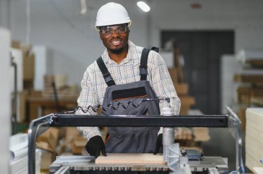 Marangoz, yoğun bir mobilya fabrikasında ahşap paneller keserken, marangoz kullanıyordu. Yetenekli işçilik ve modern teknoloji sergiliyordu.
