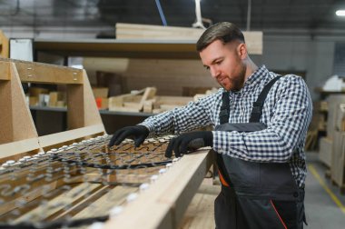 Marangoz ahşap kanepe çerçevesine yayları dikkatlice yerleştiriyor, işçiliğe ve mobilya üretimindeki hassasiyete odaklanıyor