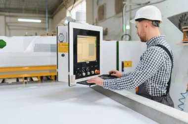 Bir mobilya fabrikasında güvenlik kaskı takan marangoz, üretimde hassasiyet ve verimliliğe odaklanıyor.