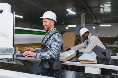 Afrikalı Amerikalı ve Avrupalı işçiler bir fabrikada mobilya üretiyorlar, yüksek kaliteli ahşap kanepeler üretmek için cnc makineleri kullanıyorlar.