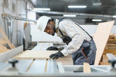 Afro-Amerikan işçiler mobilya fabrikasındaki bir makinede ahşap işiyle uğraşıyorlar, el işi ve üretim uzmanlığı sergiliyorlar.