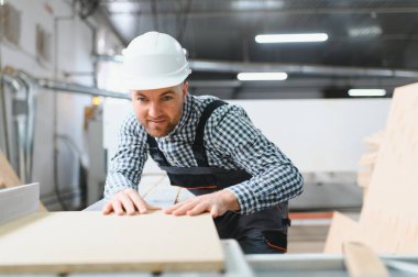 Mobilya fabrikasında çalışan işçiler, hassas ve uzman bir şekilde kanepe üretimi için ahşap bileşenler üretmeye odaklanan bir cnc makinesi işletiyorlar.