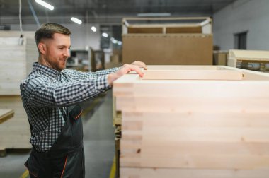 Modern bir mobilya fabrikasında ahşap bir çerçeve monte eden yetenekli işçiler. Kanepe yapımında ustalık ve hassasiyet sergiliyorlar.