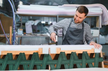 Marangoz, mobilya fabrikasının döşemelerini zımbalamak için zımba tabancası kullanıyor.