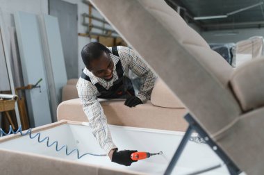 Marangoz, hareketli bir mobilya fabrikasında yeni bir kanepe yapmak için özenle çalışıyor. Yetenekli bir işçilik ve detaylara dikkat çekiyor.