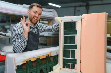 Marangoz, hareketli bir mobilya fabrikasında kanepeyi ustalıkla monte ederken iyi bir tabela hazırlıyor.