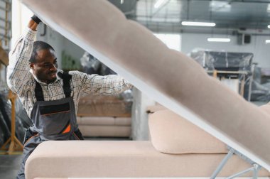 Marangoz mobilya fabrikasında kanepe monte ederek döşenmiş mobilya işçiliğinin karmaşık üretim sürecini vurguluyor.