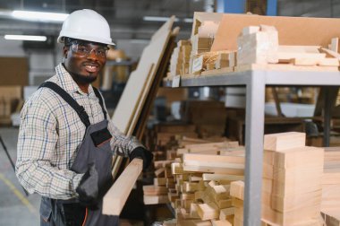 Gülümseyen marangoz mobilya fabrikası deposunda ahşap döşeme, kaliteli malzemeler ve mobilya üretiminde işçilik sergiliyor.
