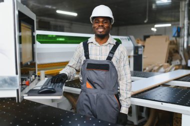 Kanepe üretimine odaklanmış bir mobilya fabrikasında CNC makinesini yöneten Afrikalı Amerikalı bir işçi. Ahşap malzemelerle sanayi