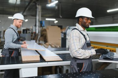 Marangozlar bir mobilya fabrikasında ahşap paneller ve bilgisayar sayısal kontrol makinesiyle çalışarak kanepeler için parça üretiyorlar.