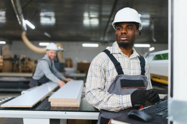 İki fabrika işçisi bir mobilya fabrikasında cnc makinesi çalıştırıyor, kanepeler için ahşap parçalar üretiyorlar.