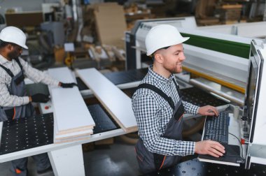 İki marangoz mobilya üreten bir mobilya fabrikasında ahşap ve bilgisayar sayısal kontrol makinesiyle çalışıyor.