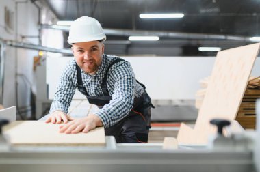 Yetenekli bir marangoz, bir mobilya üretim tesisinde kesin kesim ve şekillendirme için ahşap paneli dikkatlice yerleştiriyor.