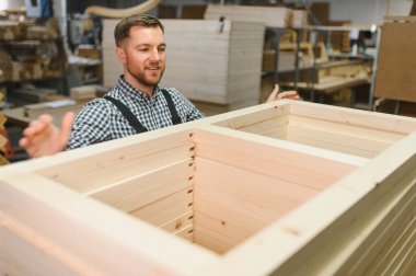 Marangoz bir atölyede mobilya için ahşap çerçeve sunuyor, marangozluk ve ahşap işçiliği sergiliyor