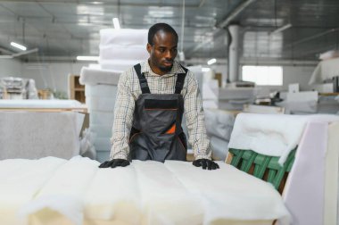 Mobilya fabrikasında malzeme inceleyen yetenekli bir zanaatkar yüksek kaliteli kanepe üretimi sağlıyor.