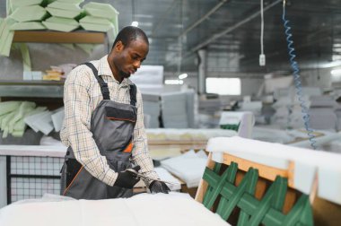 Meşgul bir mobilya fabrikasında koltuklar için döşeme kumaşı kesen Afrikalı Amerikalı işçiler, mobilya üretiminde marifetli işçilik sergiliyorlar.