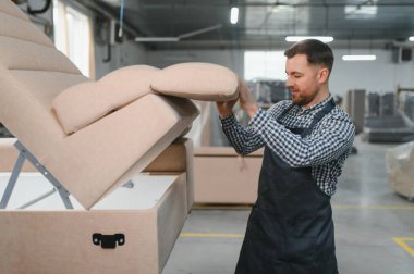 Marangoz mobilya fabrikasında kanepe monte ediyor, el yapımı mobilyaların karmaşık üretim sürecini gözler önüne seriyor.