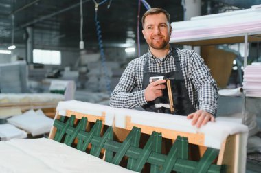 Marangoz bir mobilya atölyesinde kanepe çerçevesi inşa ediyor. Pnömatik zımba tabancasını ustalıkla kaliteli işçilik yaratmak için kullanıyor.