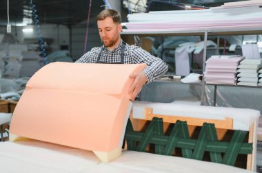 Marangoz hareketli bir mobilya fabrikasında kanepe monte ediyor, rahat ev mobilyaları yaratmak için ustalıkla köpük ve ahşapla çalışıyor.