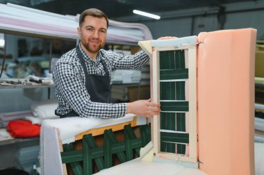 Zanaatkar ahşap mobilya çerçevesini elastik ağ ile birleştiriyor, mobilya fabrikasında döşenmiş rahat kanepe için zemin oluşturuyor.