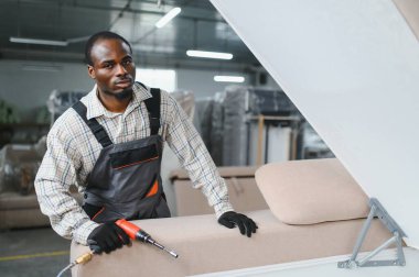 Marangoz mobilya fabrikasında kanepe monte ediyor. Pnömatik tornavida ustalıkla kaliteli el yapımı parçalar yapıyor.