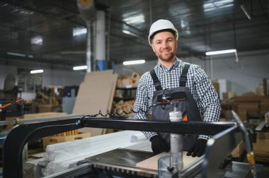 Becerikli bir marangoz, cnc makinesi kullanıyor, hareketli bir mobilya fabrikasında hassas ahşap parçaları yapıyor, uzmanlık ve modern imalat sergiliyor.