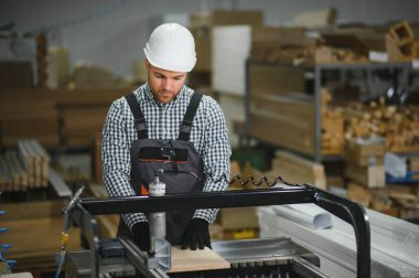 Marangoz, yoğun bir atölye ortamında hassas ve uzman mobilya parçaları üreterek bir cnc makinesi çalıştırıyor.