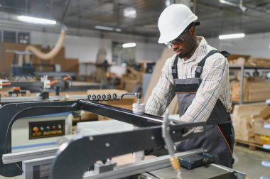 Becerikli marangoz, cnc makinesi kullanıyor. Hareketli mobilya fabrikasında ahşap parçaları dikkatlice hazırlıyor.