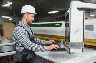 Mobilya fabrikasında çalışan bir işçi kanepe üretimi, modern marangozluk teknolojisi ve zanaatkarlığı için bir cnc makinesi kullanıyor.