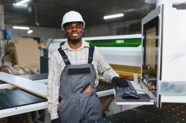Marangoz, hareketli bir mobilya fabrikasında ahşap işleme için bir cnc makinesi çalıştırıyor. Modern teknoloji ve marangozluk sergiliyor.