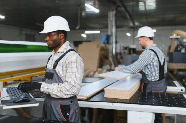 Modern bir mobilya fabrikasında kanepeler için ahşap parçalar üreten iki fabrika işçisi.