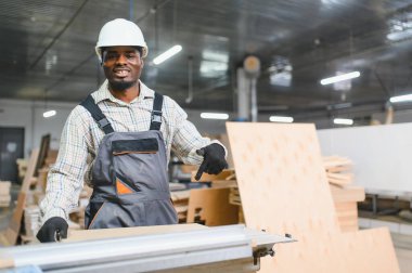 Afro-Amerikan marangoz mobilya fabrikasında çalışırken ahşap işçiliğini işaret ediyor.