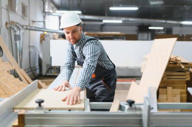 Becerikli marangoz modern cnc makinesi üzerine ahşap panel dikkatlice yerleştirerek, mobilya üretimi için hassas kesinti sağlar