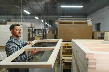 Marangoz mobilya fabrikasında kanepe için ahşap çerçeve inceliyor, döşenmiş mobilya üretim süreci