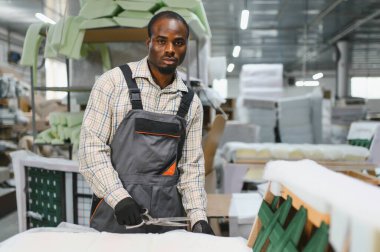 Afrika kökenli Amerikalı işçiler bir mobilya fabrikasında maharetli bir şekilde kanepe monte ediyorlar. Etrafı alet ve malzemelerle çevrili. İşçiliği ve hassasiyeti vurguluyorlar.