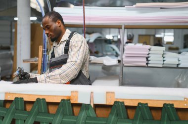 Özel aletler ve malzemeler kullanarak bir mobilya fabrikasında kanepe montajında çalışan yetenekli bir zanaatkar.