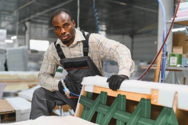 Marangoz, mobilya fabrikasındaki ahşap çerçeveyi onarmak için pnömatik zımba tabancası kullanıyor.